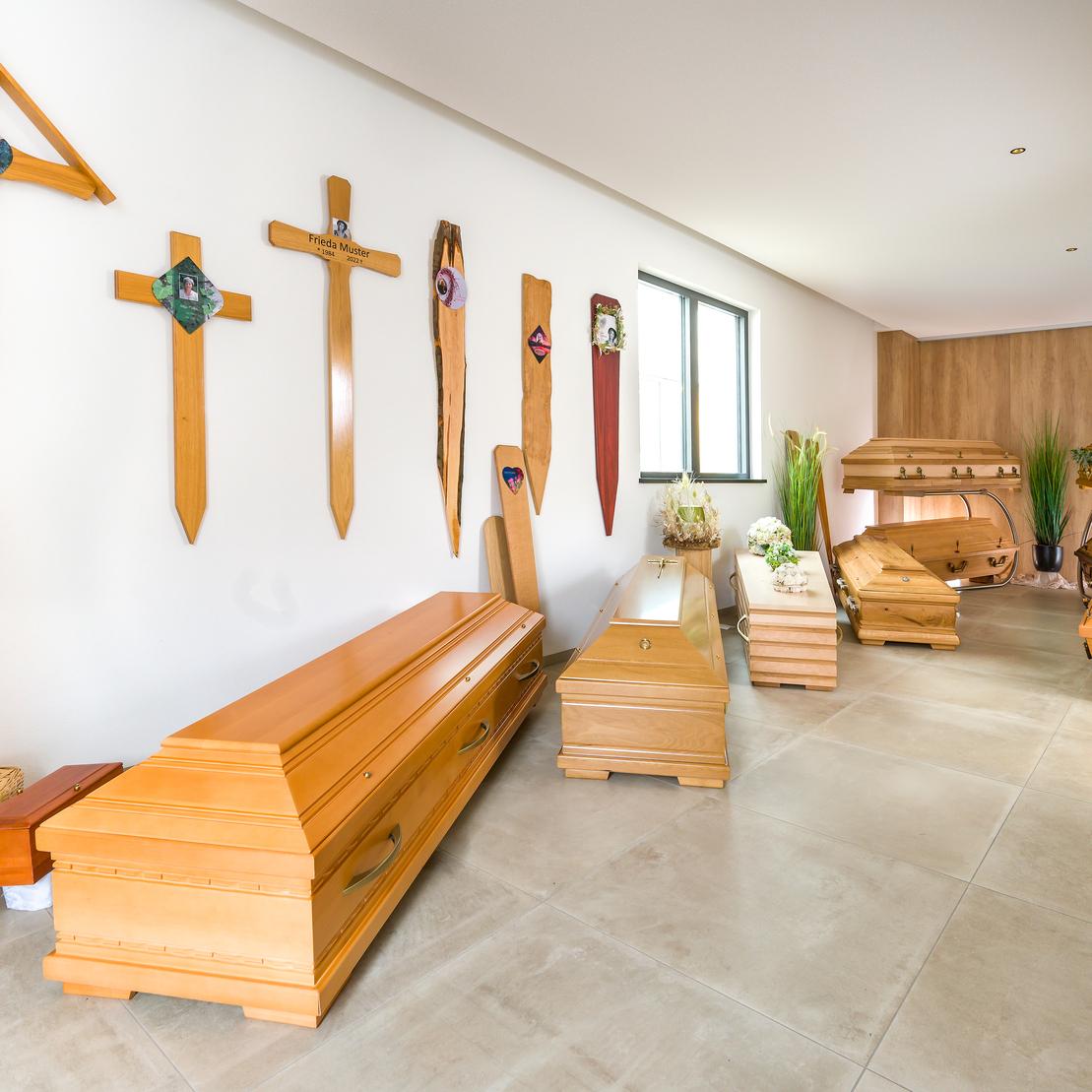 Raum mit mehreren Holzteilen, darunter Särge und Wände mit Holzkreuzen und dekorativen Elementen.
