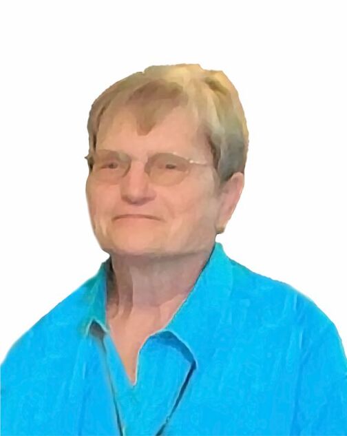 Portr&auml;t einer &auml;lteren Frau mit Brille, die ein hellblaues Hemd tr&auml;gt, vor einem hellen Hintergrund.