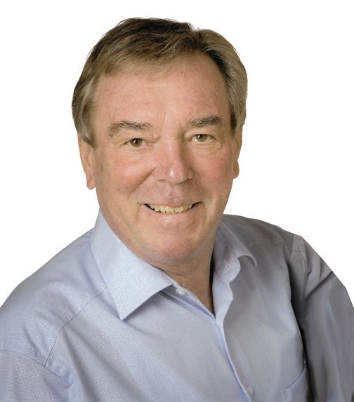 L&auml;chelnder Mann mit kurzen, grauen Haaren, tr&auml;gt ein hellblaues Hemd vor einem wei&szlig;en Hintergrund.