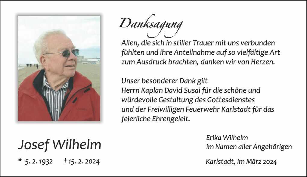 Portrait eines &auml;lteren Mannes mit Brille und roter Jacke, blickt l&auml;chelnd in die Ferne am Strand.