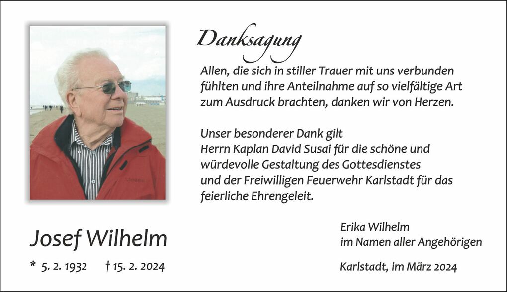 Portrait eines &auml;lteren Mannes mit Brille und roter Jacke, blickt l&auml;chelnd in die Ferne am Strand.