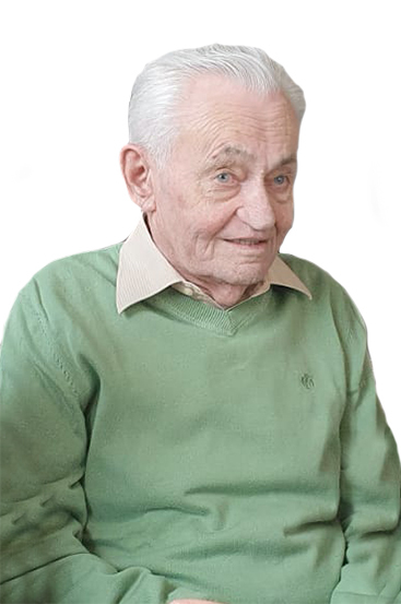 Ein &auml;lterer Mann mit grauen Haaren tr&auml;gt einen gr&uuml;nen Pullover und l&auml;chelt freundlich in die Kamera.