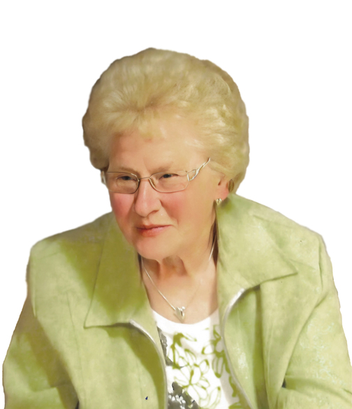 &Auml;ltere Frau mit blonden, lockigen Haaren und Brille tr&auml;gt eine helle Jacke und l&auml;chelt leicht. Hintergrund ist wei&szlig;.