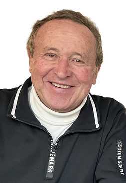 L&auml;chelnder &auml;lterer Mann in schwarzer Zip-Jacke mit wei&szlig;em Rollkragenpullover vor einem wei&szlig;en Hintergrund.
