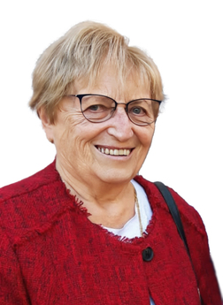 L&auml;chelnde &auml;ltere Frau mit kurzen, blonden Haaren, Brille und rotem Blazer, vor wei&szlig;em Hintergrund.