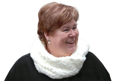 L&auml;chelnde Frau mit kurzen, braunen Haaren und einem wei&szlig;en Loop-Schal vor wei&szlig;em Hintergrund.