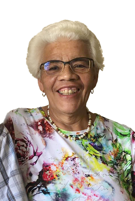 L&auml;chelnde &auml;ltere Frau mit kurzer, wei&szlig;er Frisur und Brille, tr&auml;gt ein buntes, blumiges Oberteil und eine Perlenkette.