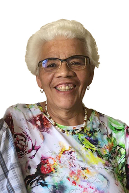 L&auml;chelnde &auml;ltere Frau mit kurzer, wei&szlig;er Frisur und Brille, tr&auml;gt ein buntes, blumiges Oberteil und eine Perlenkette.