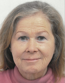 Portr&auml;t einer &auml;lteren Frau mit blonden Haaren, die in einem rosa Pullover l&auml;chelt und den Betrachter anblickt.