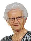 Portr&auml;t einer &auml;lteren Frau mit grauen Haaren, Brille und Perlenkette, l&auml;chelt vor einem wei&szlig;en Hintergrund.