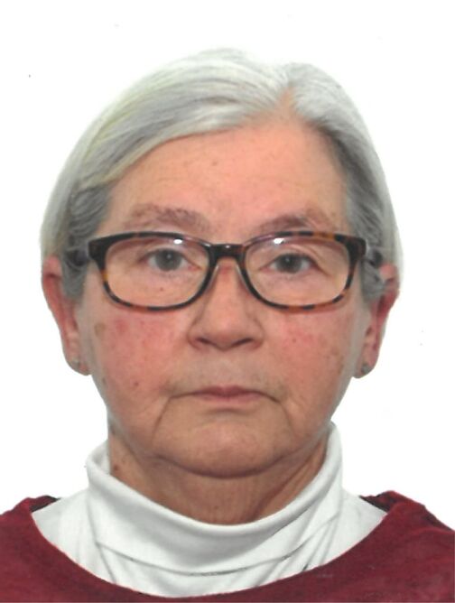 Portr&auml;t einer &auml;lteren Frau mit grauen Haaren, Brille und wei&szlig;er Bluse, vor neutralem Hintergrund.