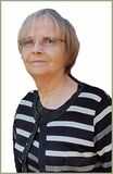 Portr&auml;t einer &auml;lteren Frau mit Brille, die ein gestreiftes Oberteil tr&auml;gt, vor einem wei&szlig;en Hintergrund.