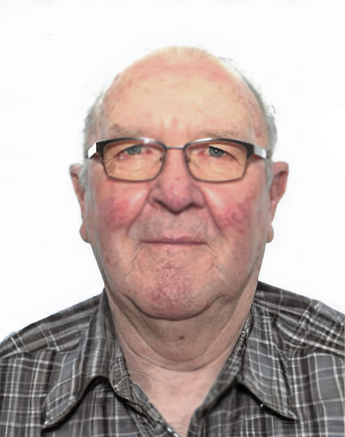 Portr&auml;t eines &auml;lteren Mannes mit Brille und kariertem Hemd vor einfarbigem Hintergrund.