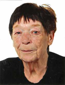 Portr&auml;t einer &auml;lteren Frau mit kurzen, dunklen Haaren und einem neutralen Gesichtsausdruck, in schwarzer Kleidung.