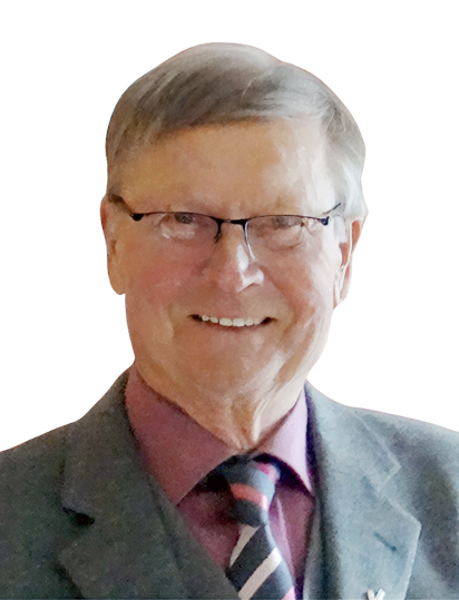 L&auml;chelnder &auml;lterer Mann mit Brille, grau-silbernem Haar und Anzug, vor wei&szlig;em Hintergrund.