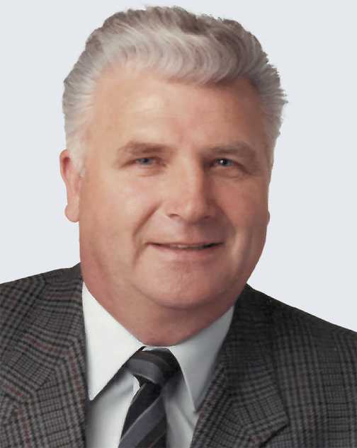 Portr&auml;t eines Mannes mit kurzem, grauem Haar und einem schwarzen Anzug, der freundlich in die Kamera l&auml;chelt.