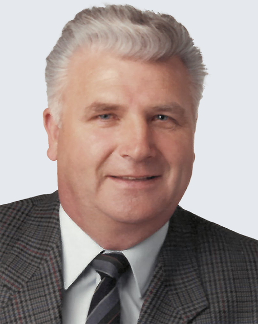 Portr&auml;t eines Mannes mit kurzem, grauem Haar und einem schwarzen Anzug, der freundlich in die Kamera l&auml;chelt.