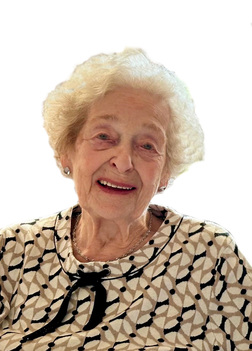 &Auml;ltere Frau mit lockigem, grauem Haar l&auml;chelt, tr&auml;gt ein gemustertes Oberteil und sitzt vor neutralem Hintergrund.