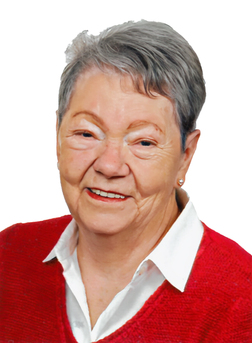 Portr&auml;t einer &auml;lteren Frau mit grauen Haaren, die ein rotes Oberteil und ein wei&szlig;es Hemd tr&auml;gt, l&auml;chelnd vor wei&szlig;em Hintergrund.