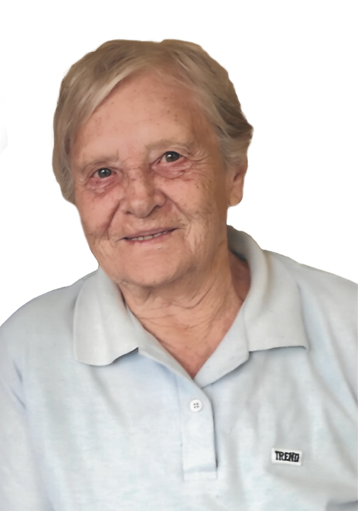 Portr&auml;t einer &auml;lteren Frau mit kurzem, grauem Haar, die in einem hellblauen Poloshirt l&auml;chelt.