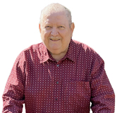 Lächelnder älterer Mann mit kurzen grauen Haaren, in rot-gestreiften Hemd, vor einem weißen Hintergrund.