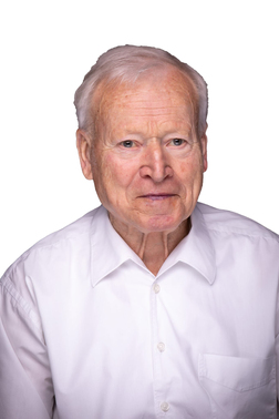 &Auml;lterer Mann mit wei&szlig;em Hemd, direkt in die Kamera schauend, vor einem wei&szlig;en Hintergrund.