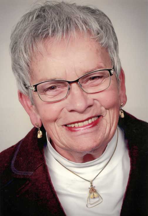 Portrait einer &auml;lteren Frau mit grauem Haar, Brille, Schmuck und Smiling auf neutralem Hintergrund.