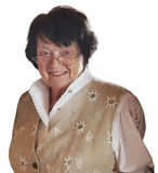 L&auml;chelnde &auml;ltere Frau mit Brille in eleganter Bluse und bestickter Weste vor wei&szlig;em Hintergrund.