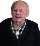 Portr&auml;t eines &auml;lteren Mannes mit freundlichem Gesicht, trug einen schwarzen Pullover &uuml;ber einem karierten Hemd.