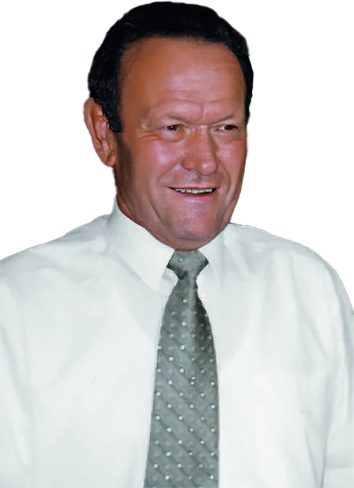 Portr&auml;t eines Mannes mit braunen Haaren, wei&szlig;em Hemd und grauer Krawatte mit Punkten, l&auml;chelnd vor wei&szlig;em Hintergrund.