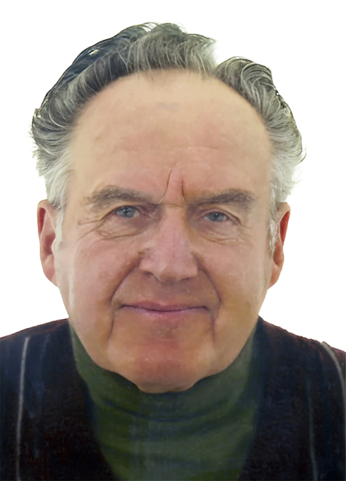 Portr&auml;t eines &auml;lteren Mannes mit grauen Haaren, der in einem dunkelgr&uuml;nen Oberteil l&auml;chelt. Hintergrund ist wei&szlig;.