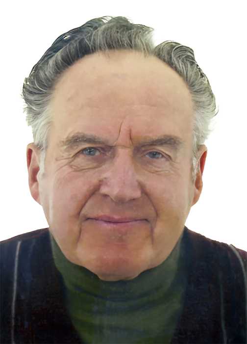 Portr&auml;t eines &auml;lteren Mannes mit grauen Haaren, der in einem dunkelgr&uuml;nen Oberteil l&auml;chelt. Hintergrund ist wei&szlig;.