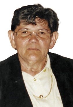 Portr&auml;t einer &auml;lteren Person mit Brille, dunklem Oberteil und heller Bluse, auf neutralem Hintergrund.