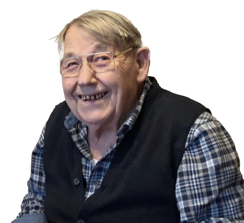 L&auml;chelnder &auml;lterer Mann mit Brille, in einer karierter Bluse und Weste, posiert vor einem wei&szlig;en Hintergrund.