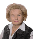 Portr&auml;t einer &auml;lteren Frau mit blonden, lockigen Haaren, die eine dunkle Weste &uuml;ber einem wei&szlig;en Hemd tr&auml;gt.