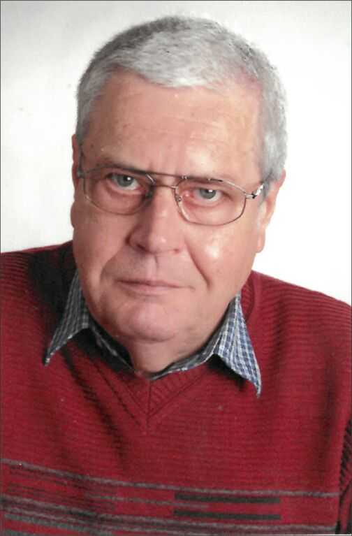 Portrait eines &auml;lteren Mannes mit Brille, grauen Haaren, rot gestreiftem Pullover und kariertem Hemd.