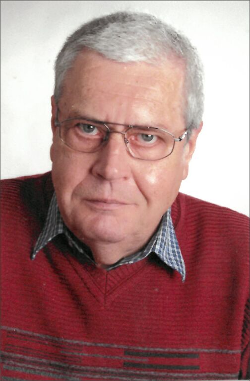 Portrait eines &auml;lteren Mannes mit Brille, grauen Haaren, rot gestreiftem Pullover und kariertem Hemd.