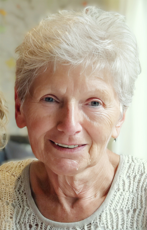 Portr&auml;t einer &auml;lteren Frau mit kurzem, grauem Haar und freundlichem Gesichtsausdruck, in einem hellen Raum.