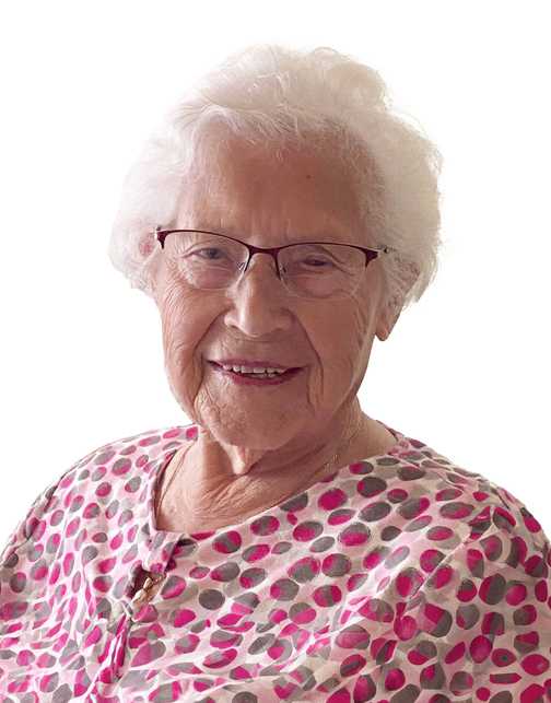 Portr&auml;t einer &auml;lteren Frau mit Brille und lockigem, wei&szlig;em Haar, die ein gepunktetes Oberteil tr&auml;gt und l&auml;chelt.