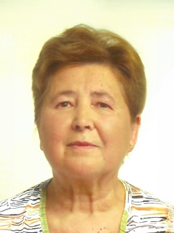 Porträt einer älteren Frau mit Kurzhaarfrisur, die freundlich in die Kamera blickt, vor hellem Hintergrund.