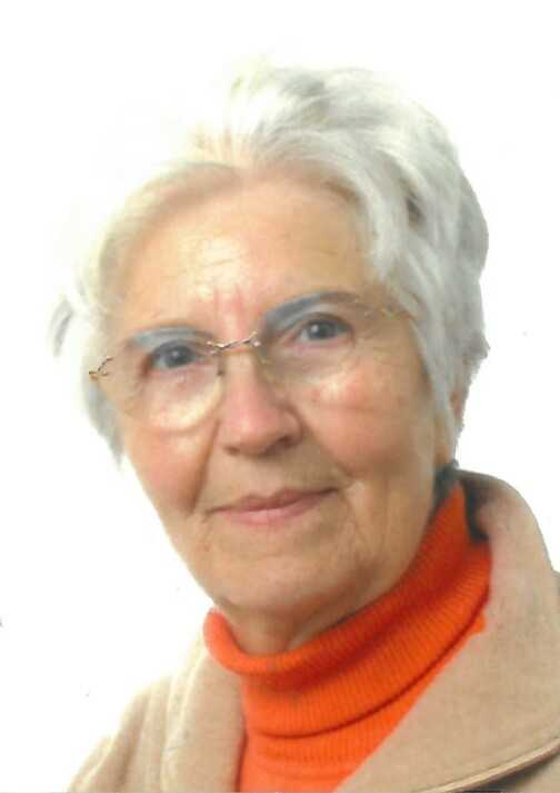 Portrait einer &auml;lteren Frau mit grauen Haaren, Brille und orangefarbenem Pullover vor wei&szlig;em Hintergrund.
