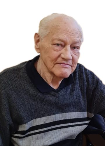 Ein &auml;lterer Mann mit grauen Haaren sitzt in einem Stuhl und tr&auml;gt einen dunkelgrauen Pullover mit Streifen.