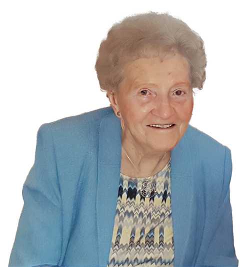 &Auml;ltere Frau mit kurzem, lockigem Haar in blauer Jacke und gemusterter Bluse l&auml;chelt in die Kamera.