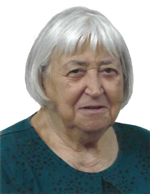 Portr&auml;t einer &auml;lteren Frau mit grau-wei&szlig;en Haaren, die ein gr&uuml;nes Oberteil mit Punkten tr&auml;gt. Sie schaut in die Kamera.