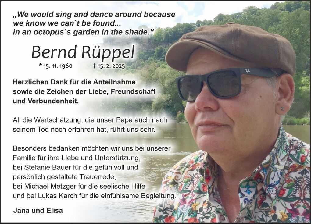 Bild zeigt eine Person mit Sonnenbrille und einem bunten Hemd, die an einem Gew&auml;sser steht, umgeben von Natur.