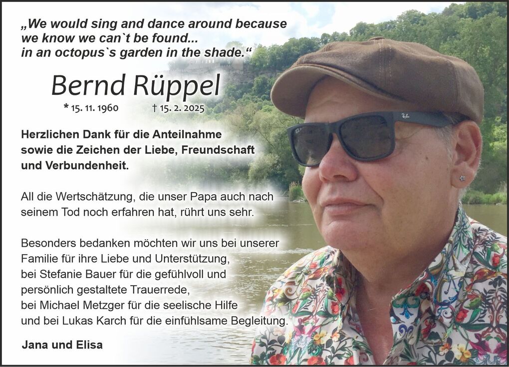 Bild zeigt eine Person mit Sonnenbrille und einem bunten Hemd, die an einem Gew&auml;sser steht, umgeben von Natur.