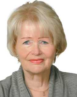 Portrait einer Frau mit blonden Haaren, die in einem grauen Oberteil vor einem wei&szlig;en Hintergrund l&auml;chelt.