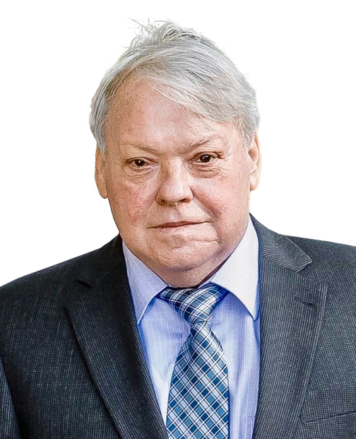 Mann mit grauem Anzug und kariertem Blau-Wei&szlig;-Tie steht vor neutralem Hintergrund und blickt direkt in die Kamera.