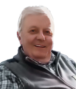 L&auml;chelnder Mann mit hellen Haaren und Weste, sitzt vor einem wei&szlig;en Hintergrund.