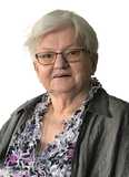 Portr&auml;t einer &auml;lteren Frau mit kurzen, grauen Haaren, Brille und blumigen Oberteil, vor wei&szlig;em Hintergrund.
